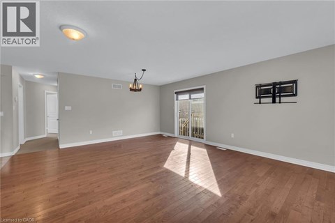 A large empty room with wooden floors and a chandelier.