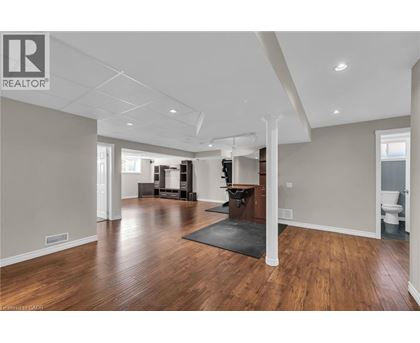 A spacious living room with hardwood floors and a black rug in the center.
