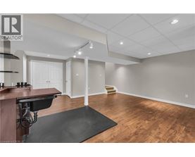 A spacious room with wooden floors and a bar area.