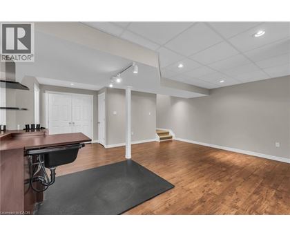 A spacious room with wooden floors and a bar area.