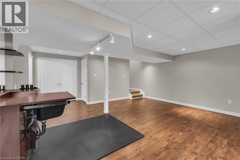 A spacious room with wooden floors and a bar area.