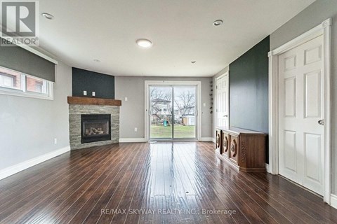 A spacious room with a fireplace and wooden floors.