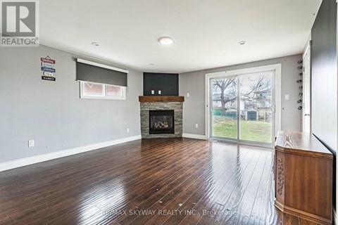 A spacious living room with wood flooring and a fireplace.