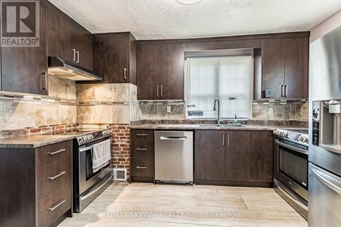 A kitchen with brown cabinets and a brick wall.