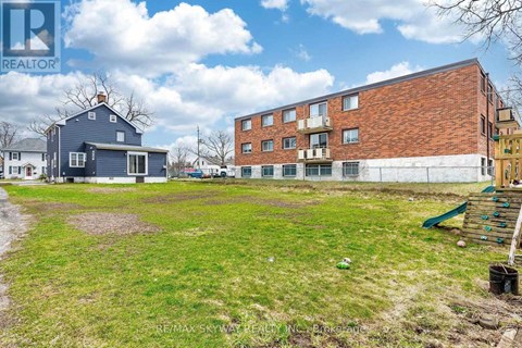 A blue house with a red brick building behind it.