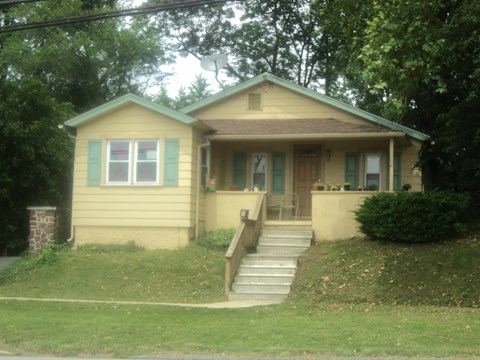 A small house with a green roof and a porch.