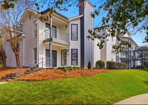 A modern two-story house with a balcony and a well-maintained lawn.