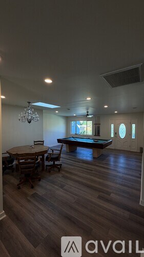 A room with a pool table and a chandelier.