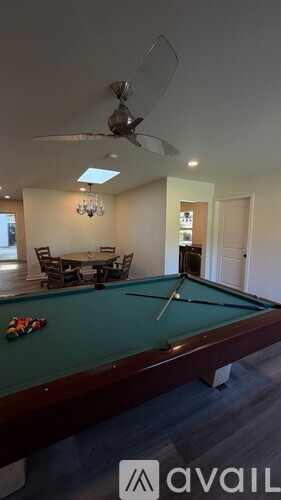 A pool table with a green felt cloth and a white cue ball on it.