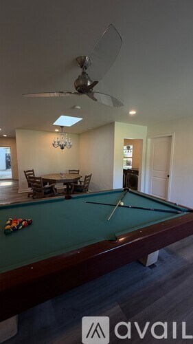 A pool table with a green felt cloth and a white cue ball on it.