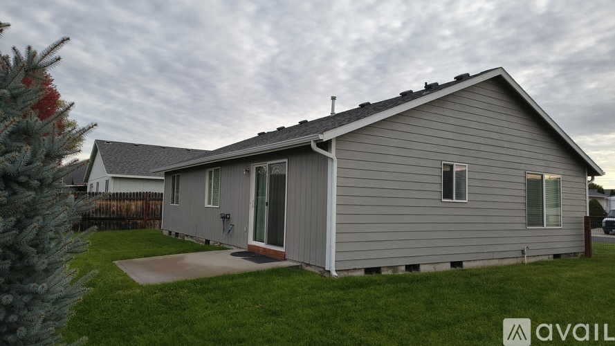 A house with a grey siding and a white door is available for rent.