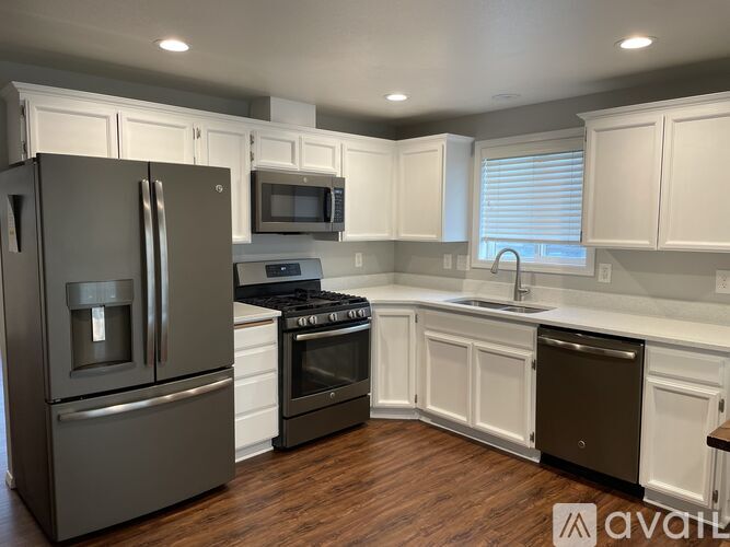 A kitchen with a refrigerator, oven, microwave, and sink.