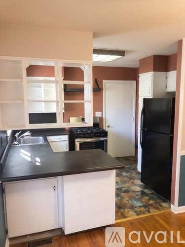 A kitchen with white cabinets and a black countertop.