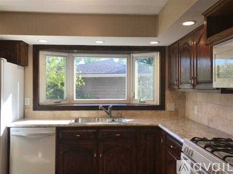 A kitchen with dark wood cabinets and a white stove top oven.