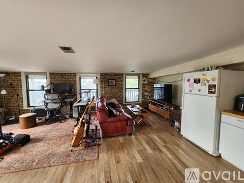 A living room with a red chair and a white refrigerator.