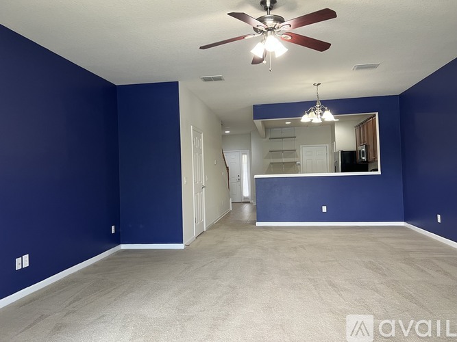 A spacious room with blue walls and a ceiling fan.