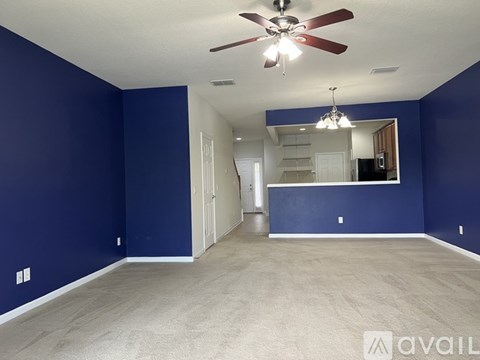 A spacious room with blue walls and a ceiling fan.