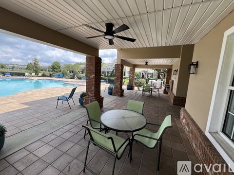 A patio with a table and chairs overlooking a pool.