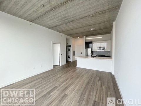 A spacious room with a concrete ceiling and wood flooring.
