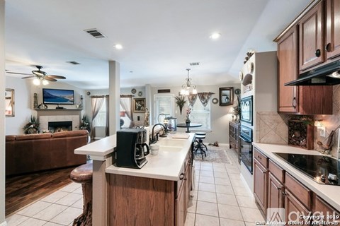 A well-lit kitchen with a bar area and a television mounted above the fireplace.