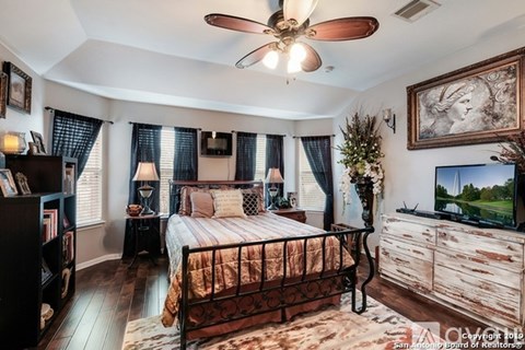 A bedroom with a bed, dresser, and a ceiling fan.