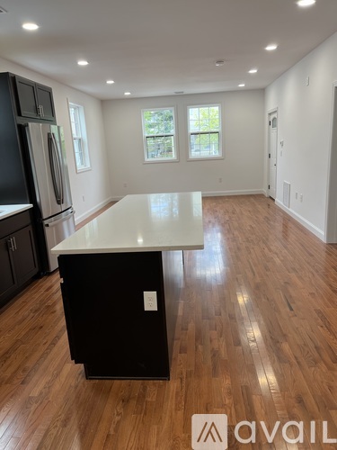 A kitchen with a black fridge and a white island.