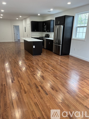 A kitchen with black cabinets and a wooden floor.