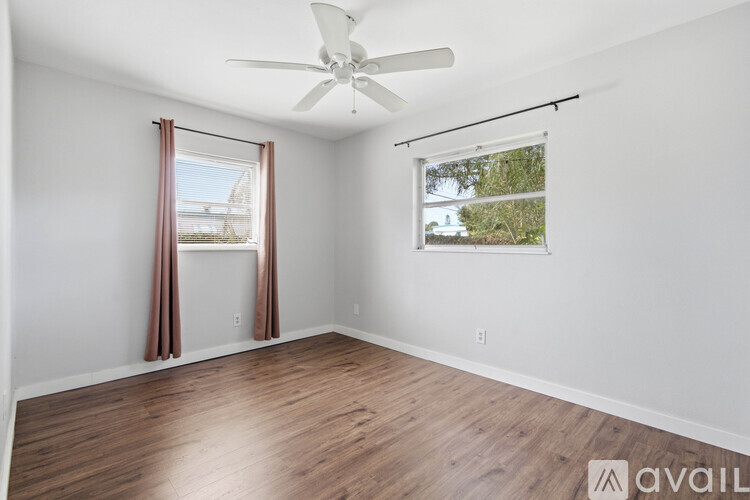 A room with a ceiling fan and a window with a view of trees.