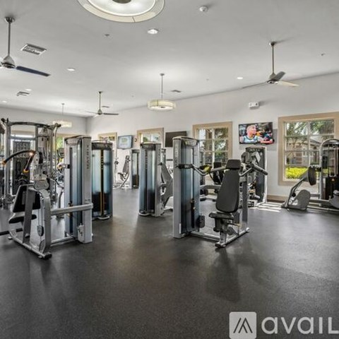 A well-equipped gym with various exercise machines and a ceiling fan.