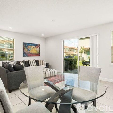 A living room with a glass table and a painting on the wall.