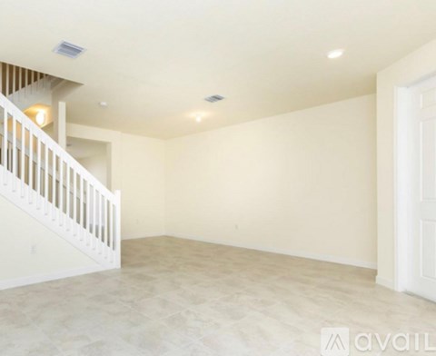 A spacious empty room with a staircase on the left side.
