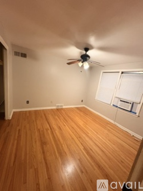 A room with wooden flooring and a ceiling fan.