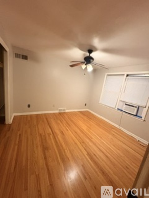 A room with wooden flooring and a ceiling fan.