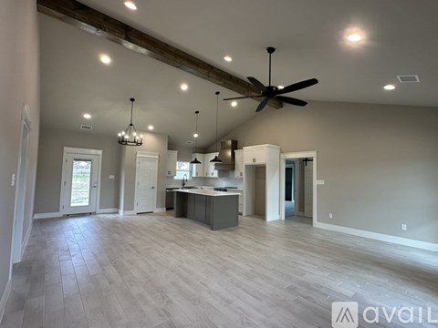A spacious kitchen and living room with a ceiling fan and lighting fixtures.