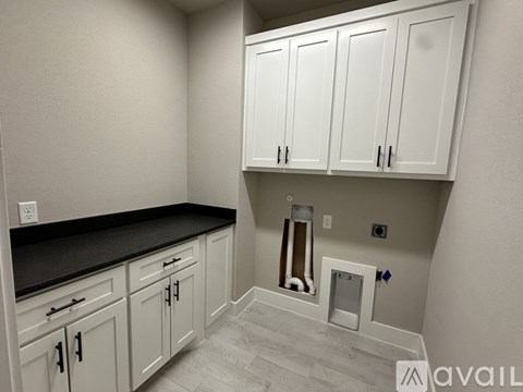 A kitchen with white cabinets and a black countertop.