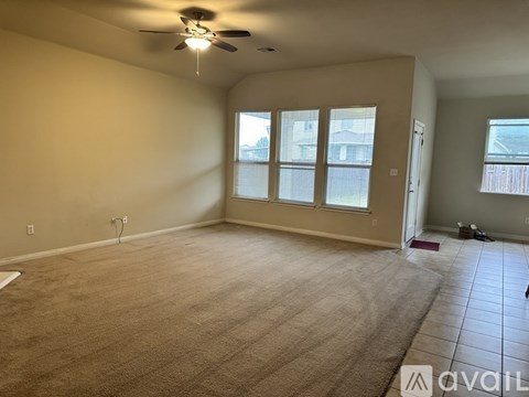 A spacious room with a ceiling fan and carpeted floor.