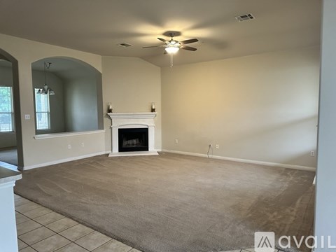 A living room with a fireplace and a ceiling fan.