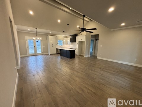 A spacious room with wooden flooring and a ceiling fan.