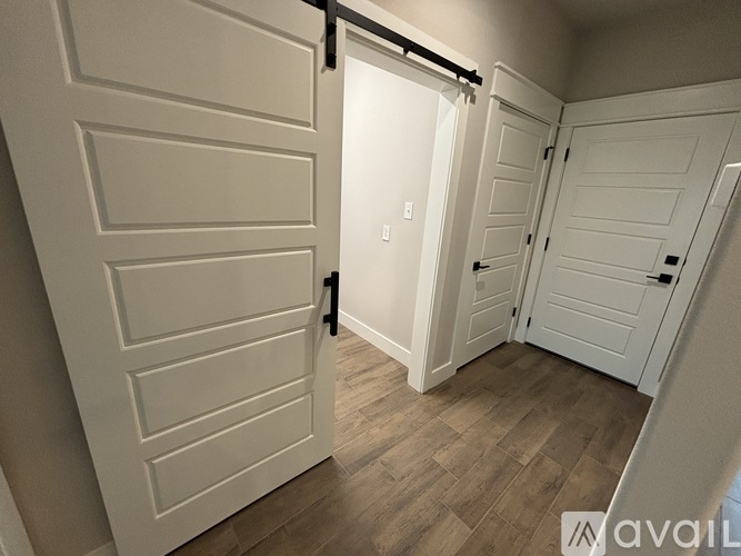 A white door with a black handle is open, revealing a hallway with two more white doors.