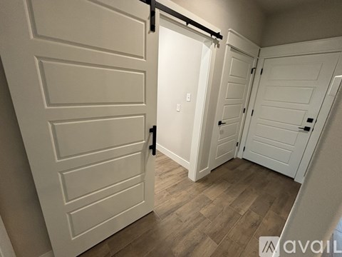A white door with a black handle is open, revealing a hallway with two more white doors.