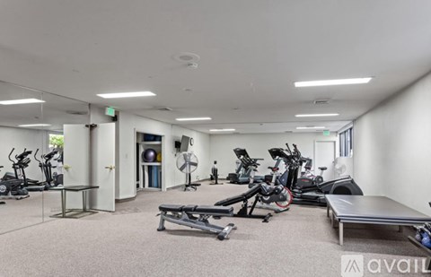 A gym with a variety of exercise equipment including treadmills, stationary bikes, and weight benches.