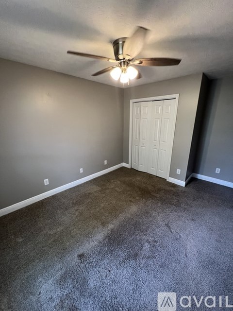 A room with a ceiling fan and a door.