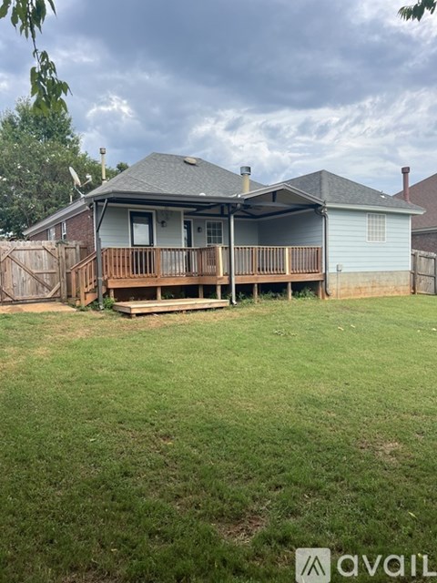 A house with a deck and a fence in the yard.