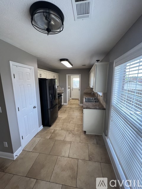 A kitchen with tile flooring and a black refrigerator.