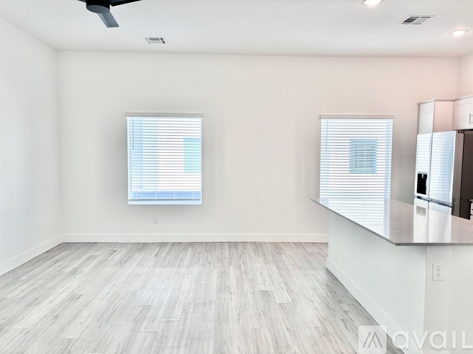 A spacious room with a large window and a wooden floor.