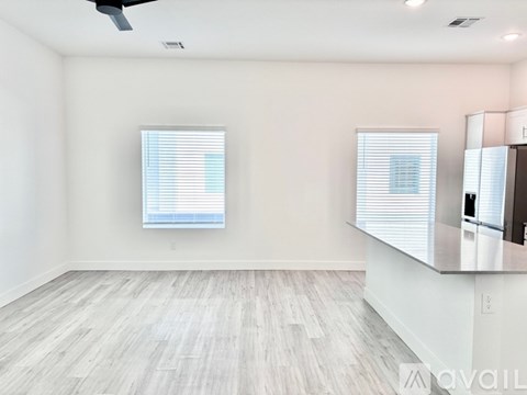 A spacious room with a large window and a wooden floor.