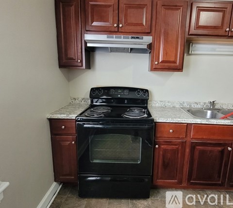 A black stove top oven in a kitchen with brown cabinets.