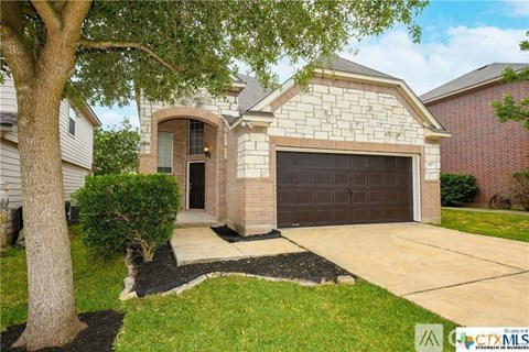 A house with a garage and a tree in front.