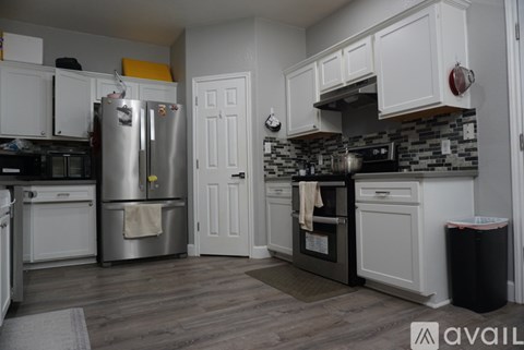 A kitchen with white cabinets and a black and white tiled backsplash.