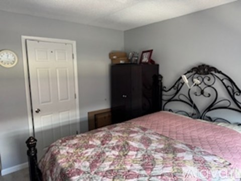 A bedroom with a bed, dresser and a door.
